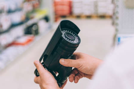 A man holds a street video camera in his hands. Concept man chooses a product in a storeの写真素材
