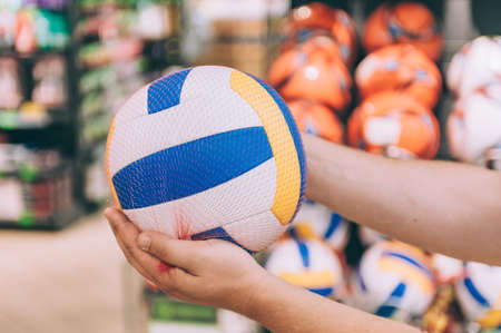 A man is holding a volleyball ball. Concept man chooses a product in a storeの写真素材