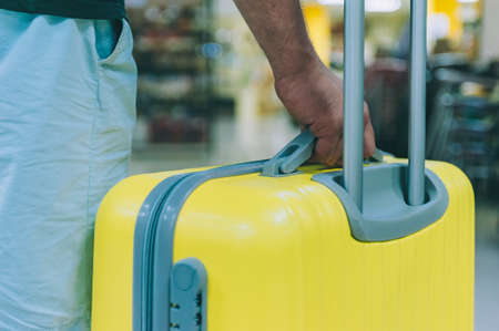 A guy with a yellow suitcase goes on a trip at the airportの写真素材