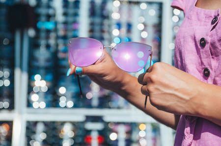 The girl chooses sunglasses on the background of glasses