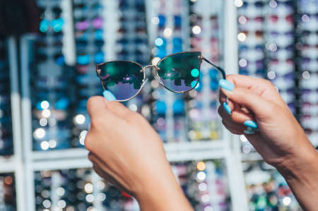 The girl chooses sunglasses on the background of glassesの写真素材