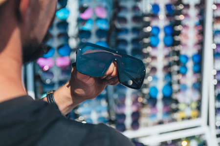 The guy chooses sunglasses on the background of glassesの写真素材