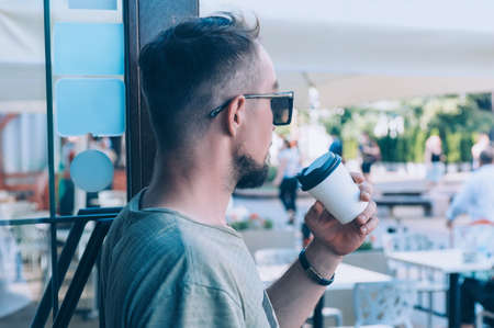 The guy is drinking coffee in a plastic cup at a cafeの写真素材