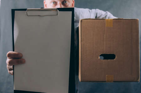 Guy with a cardboard box in his hands. Delivery service concept on dark background