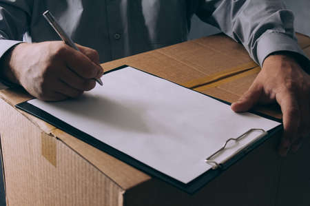 Guy with a cardboard box in his hands. Delivery service concept on dark backgroundの写真素材