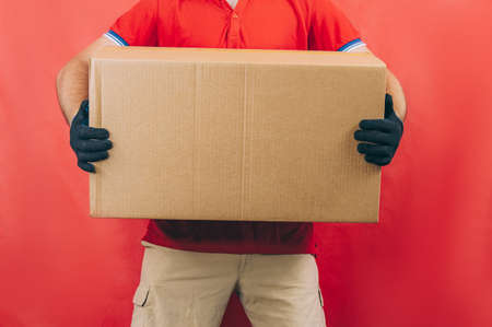 Guy with a cardboard box in his hands. Delivery service concept on red background