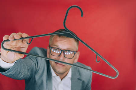 Businessman holds a hanger in his hands on a red backgroundの写真素材