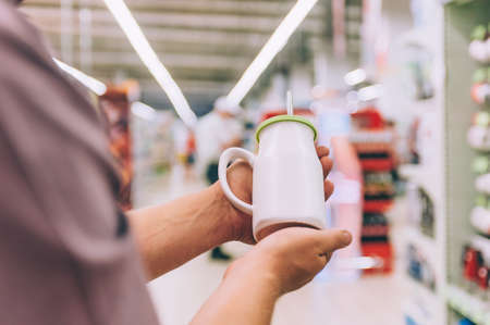 A man in a supermarket holds a cup with a straw for a drinkの写真素材