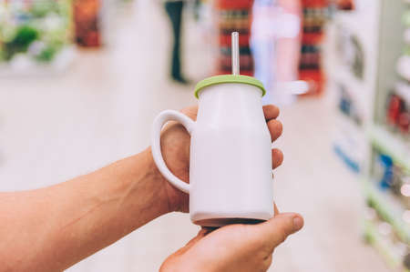 A man in a supermarket holds a cup with a straw for a drinkの写真素材