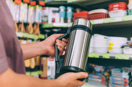 A man in a supermarket holds a thermos in his handsの写真素材