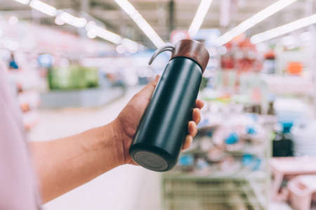 A man in a supermarket holds a flask in his handsの写真素材