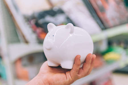 The guy in the supermarket holds a piggy bank for moneyの写真素材