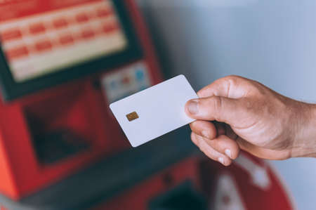 Man holds a credit card against the background of an ATM machineの写真素材