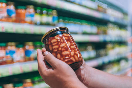 The guy in the supermarket is holding a glass jar of beansの写真素材