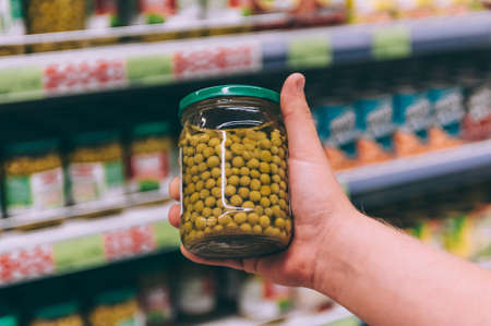 The guy in the supermarket is holding a glass jar with peasの写真素材