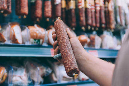A guy in a supermarket picks a sausage in a shop windowの写真素材