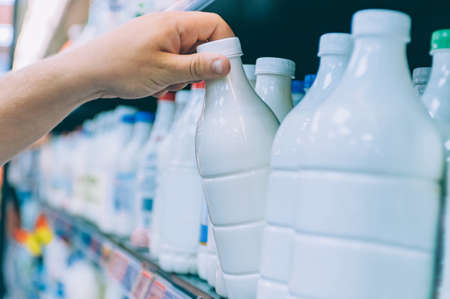 A guy in a supermarket is choosing milk in a shop windowの写真素材