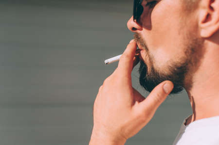 A guy with a cigarette in his hands smokesの写真素材