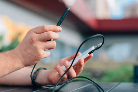 Portable charger in the hands of a person. Powerbank charges the phoneの写真素材