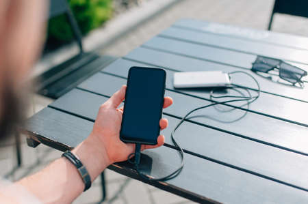 Portable charger in the hands of a person. Powerbank charges the phoneの写真素材