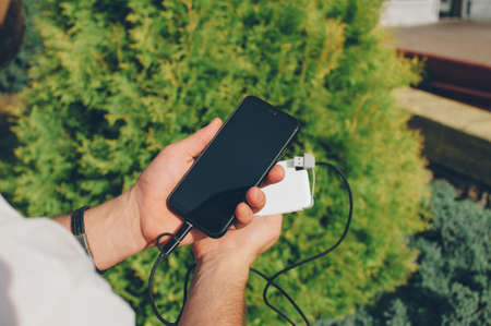 Portable charger in the hands of a person. Powerbank charges the phoneの写真素材