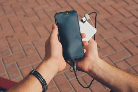 Portable charger in the hands of a person. Powerbank charges the phoneの写真素材