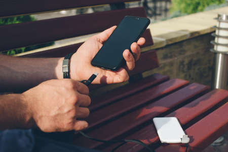 Portable charger in the hands of a person. Powerbank charges the phoneの写真素材