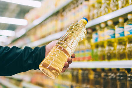A guy in a supermarket picks out oil in a shop windowの写真素材