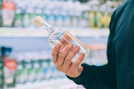 The guy is holding a bottle of vodka in the storeの写真素材