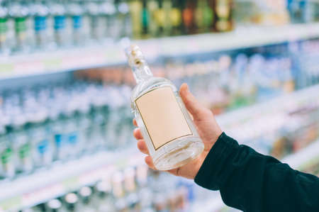 The guy is holding a bottle of vodka in the storeの写真素材