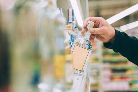 The guy is holding a bottle of vodka in the storeの写真素材
