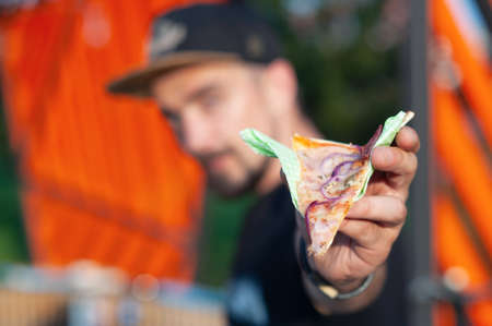 A man holds a slice of pizza in his hands. Fast food in the fresh airの写真素材