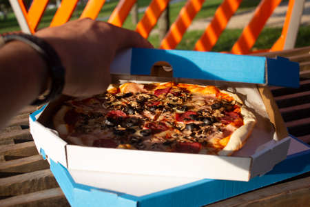 The man on the bench is eating pizza. Fast food in the fresh airの写真素材