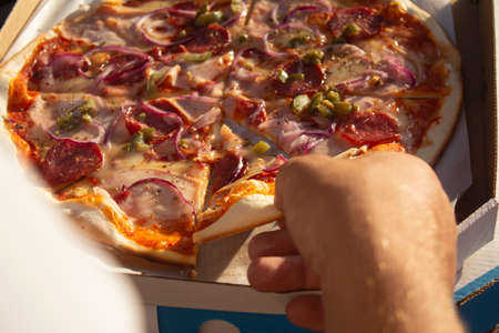 A man holds a slice of pizza in his hands. Fast food in the fresh airの写真素材