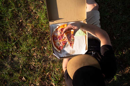 A man holds a slice of pizza in his hands. Fast food in the fresh airの写真素材