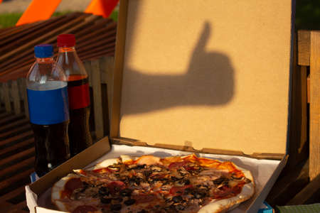 Pizza in a box and bottled soda on a bench. Fast food in the fresh airの写真素材