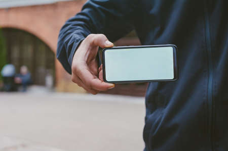 Mock-up technology. Man holds a smartphone in his hands close-upの写真素材
