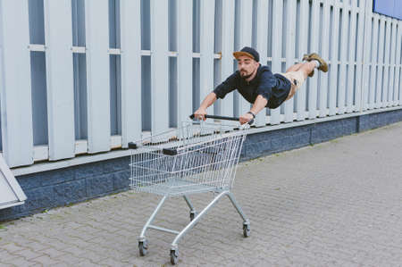 The buyer rushes to the sale. The guy flies with a supermarket trolley in his handsの写真素材