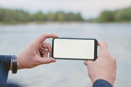 Mock-up technology. Man holds a smartphone in his hands close-upの写真素材