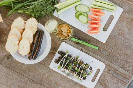 Fresh vegetables with salad and grilled sausages on a wooden table backgroundの写真素材