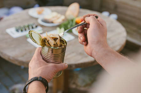 The guy eats mushrooms from a jar on the background of the tableの写真素材