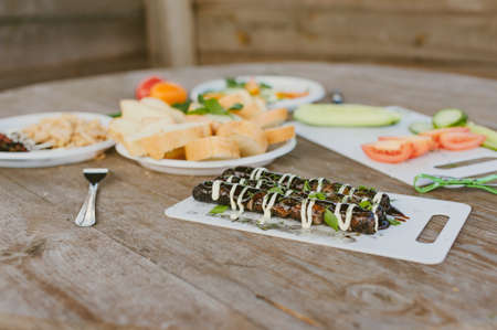 Fresh vegetables with salad and grilled sausages on a wooden table backgroundの写真素材