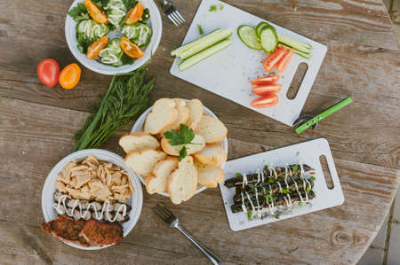 Fresh vegetables with salad and grilled sausages on a wooden table backgroundの写真素材