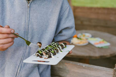 Picnic in nature. The guy is holding a tray with grilled sausagesの写真素材