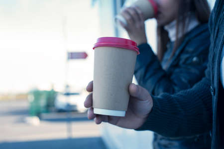A girl and a guy are drinking coffee with a glass in their handsの写真素材