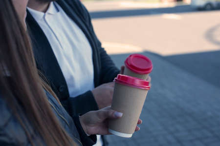 A girl and a guy are drinking coffee with a glass in their handsの写真素材