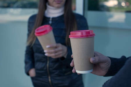 A girl and a guy are drinking coffee with a glass in their handsの写真素材