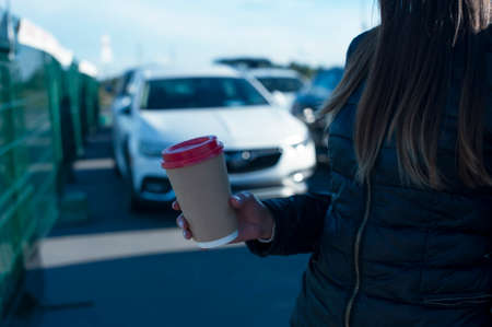 The girl and the guy drink coffee with a glass in their hands on the background of the carの写真素材