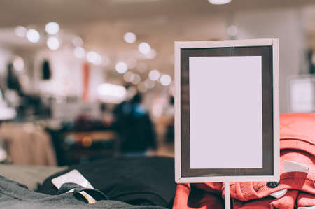 Mock up of a white signboard on the background of a store with clothesの写真素材