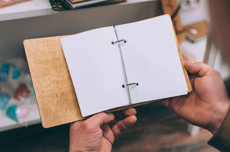 The guy holds a notebook with a craft cover in his hands